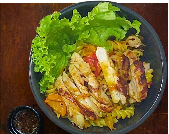 Ensalada de pasta con pollo grillado y verduras asadas, con aliño extra por separado.